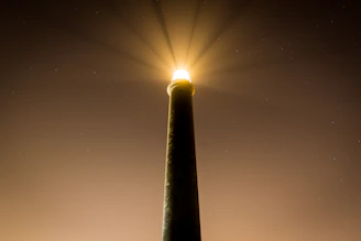 A sleek lighthouse shining light over a calm sea at dawn, symbolizing guidance.