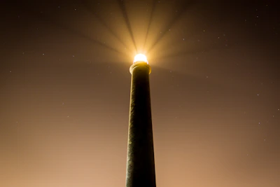 A sleek lighthouse shining light over a calm sea at dawn, symbolizing guidance.