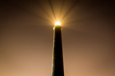 A lighthouse shining its beam over a calm sea at dusk, symbolizing guidance and clarity.