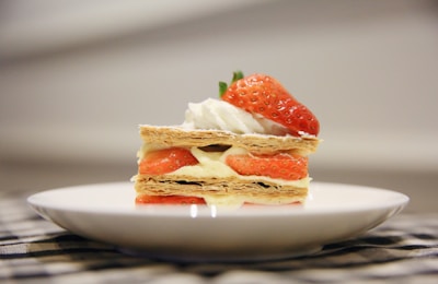 A tempting dessert with layers of cream and fresh fruit on a rustic plate.