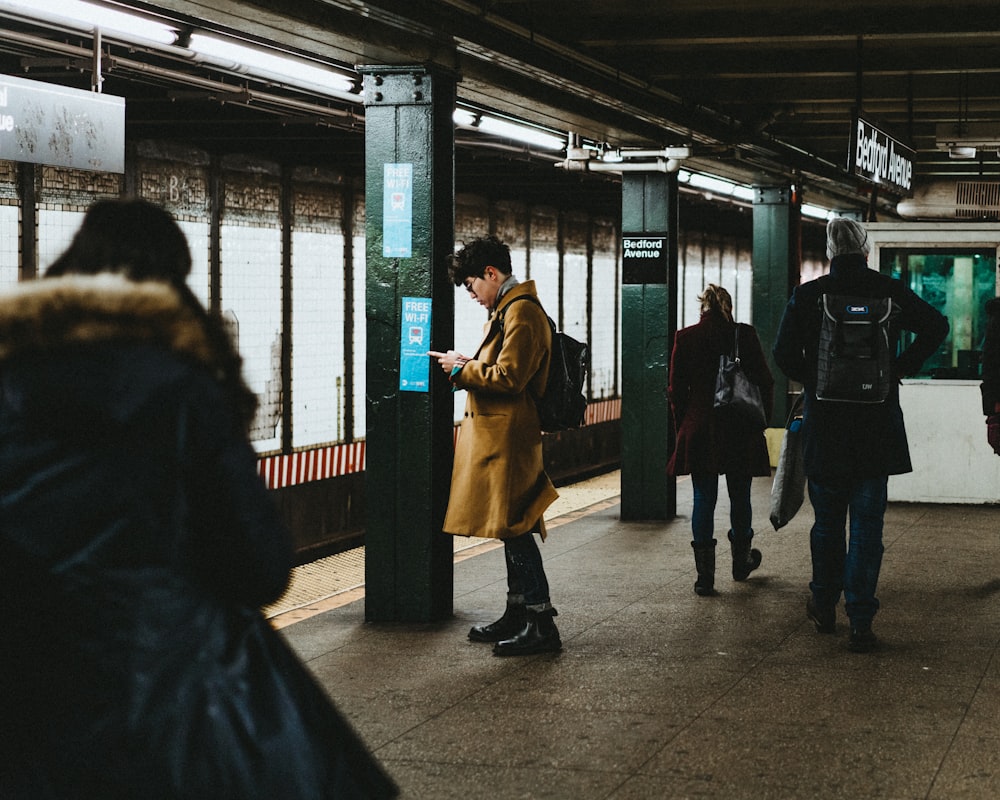 Hombre usando un teléfono inteligente dentro de la estación de tren