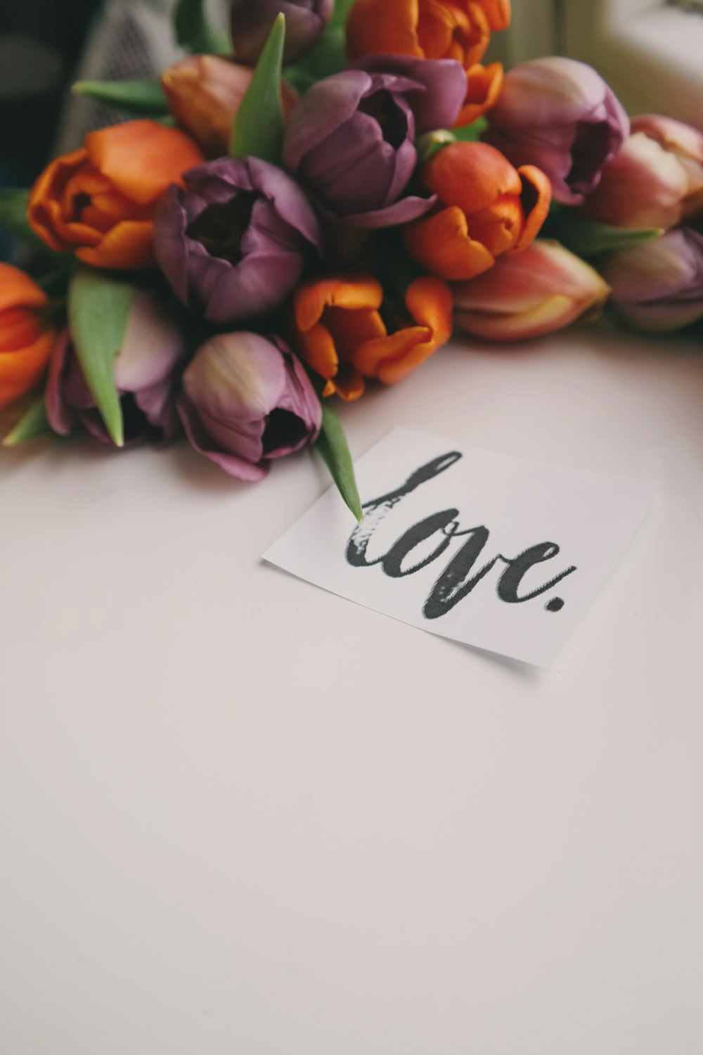 チューリップの花束、筆記体で「愛」と書かれた紙片の隣