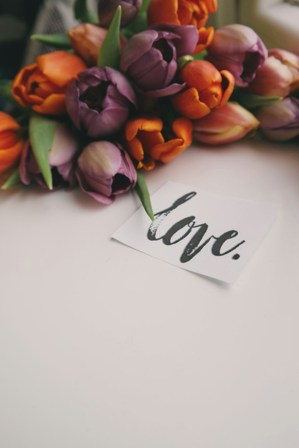 Bouquet of tulips, next to a slip of paper that reads "love" in cursive writing