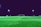 An empty artificial turf soccer field is illuminated by bright stadium lights at night. A goalpost is located in the center background with additional goalposts and various equipment placed around the field.