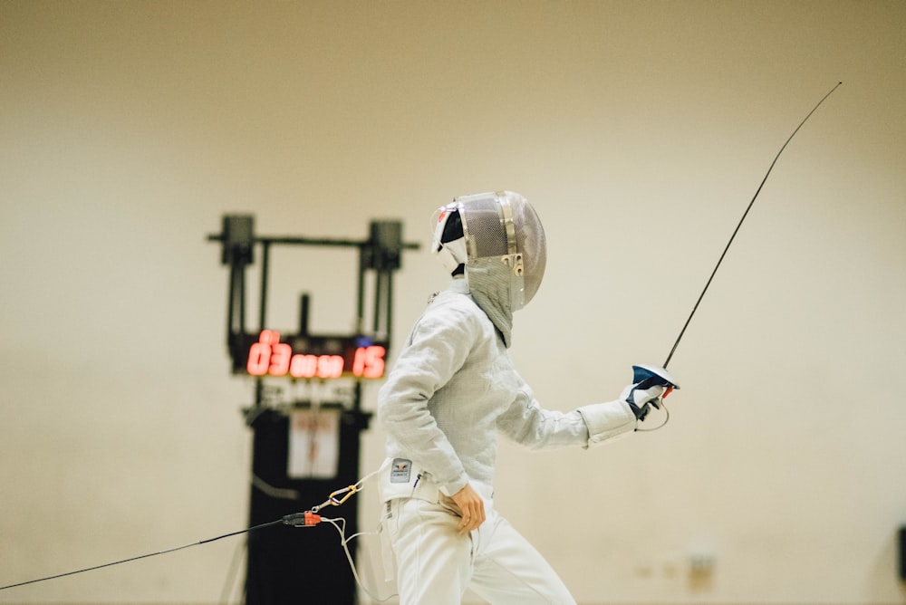 man wearing white coveralls holding fencing sword