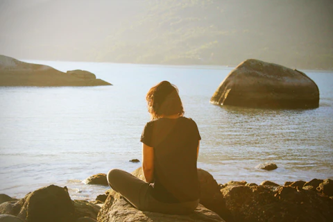 person sitting near body of water during daytime