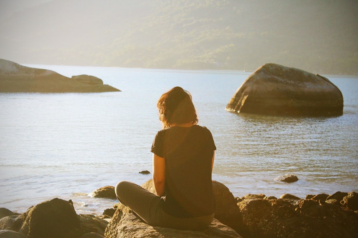 A woman meditating peacefully at sunrise