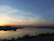 A calm lake at dawn reflecting gentle pastel colors.