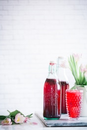 clear glass bottle beside purple flowers