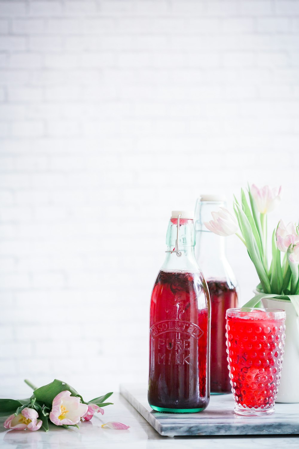 bouteille en verre transparent à côté de fleurs violettes