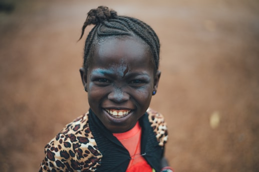 A joyful minority child wearing a crown, smiling confidently in an urban neighborhood.