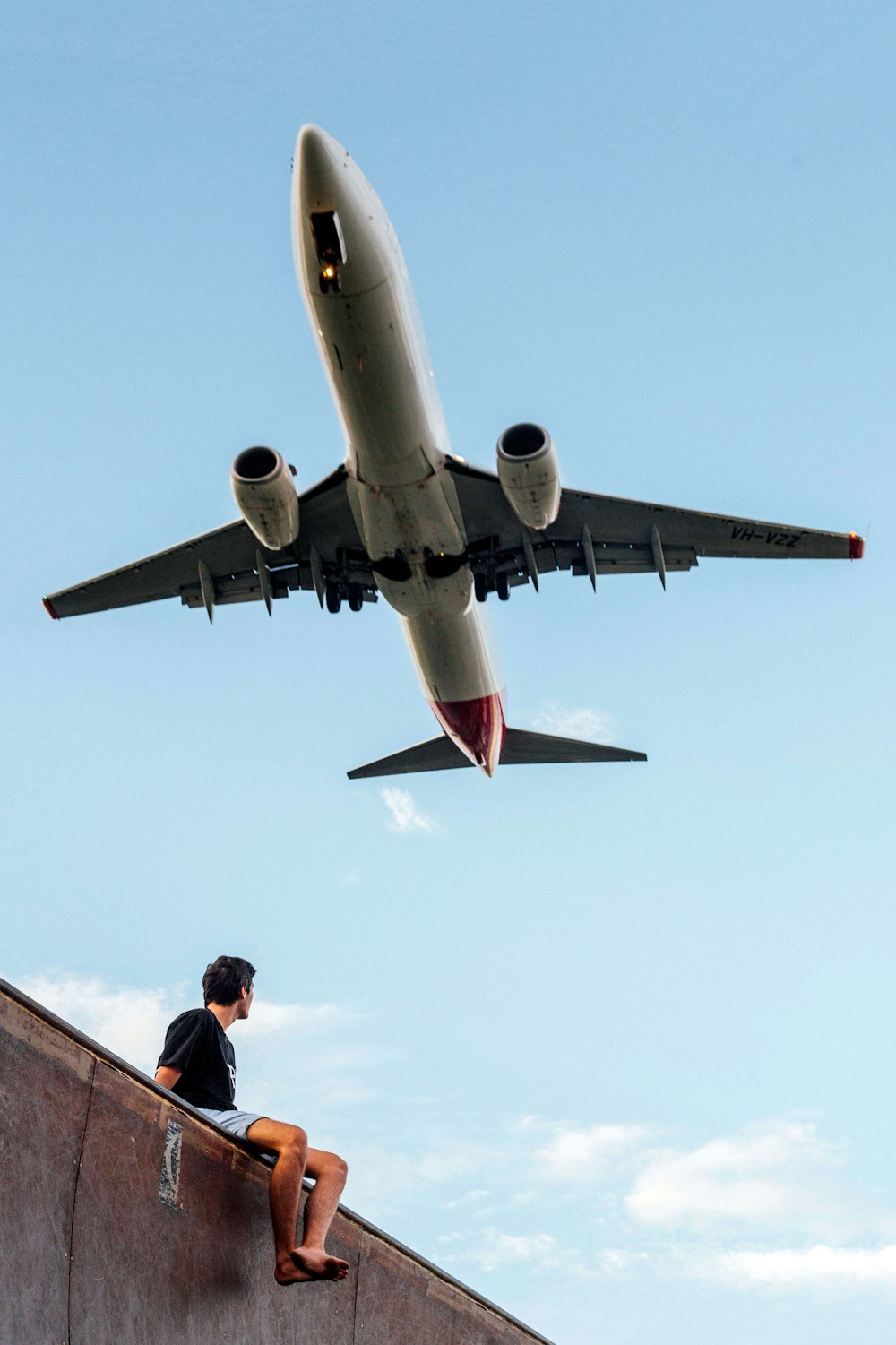 Photographie en contre-plongée d’un homme portant une chemise noire sous un avion blanc et gris