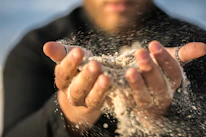 Close-up of hands gently holding a small hourglass symbolizing time and self-control.