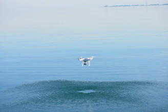 Close-up of a drone flying smoothly over a peaceful lake with mountains in the background.