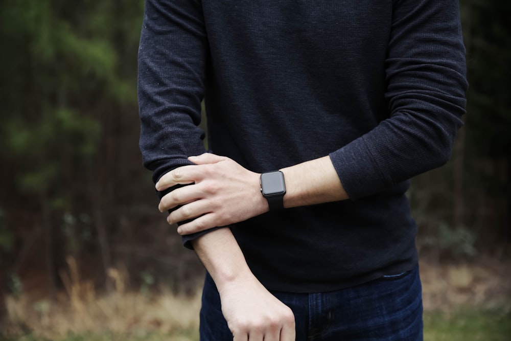 Un uomo in camicia nera tiene le mani unite