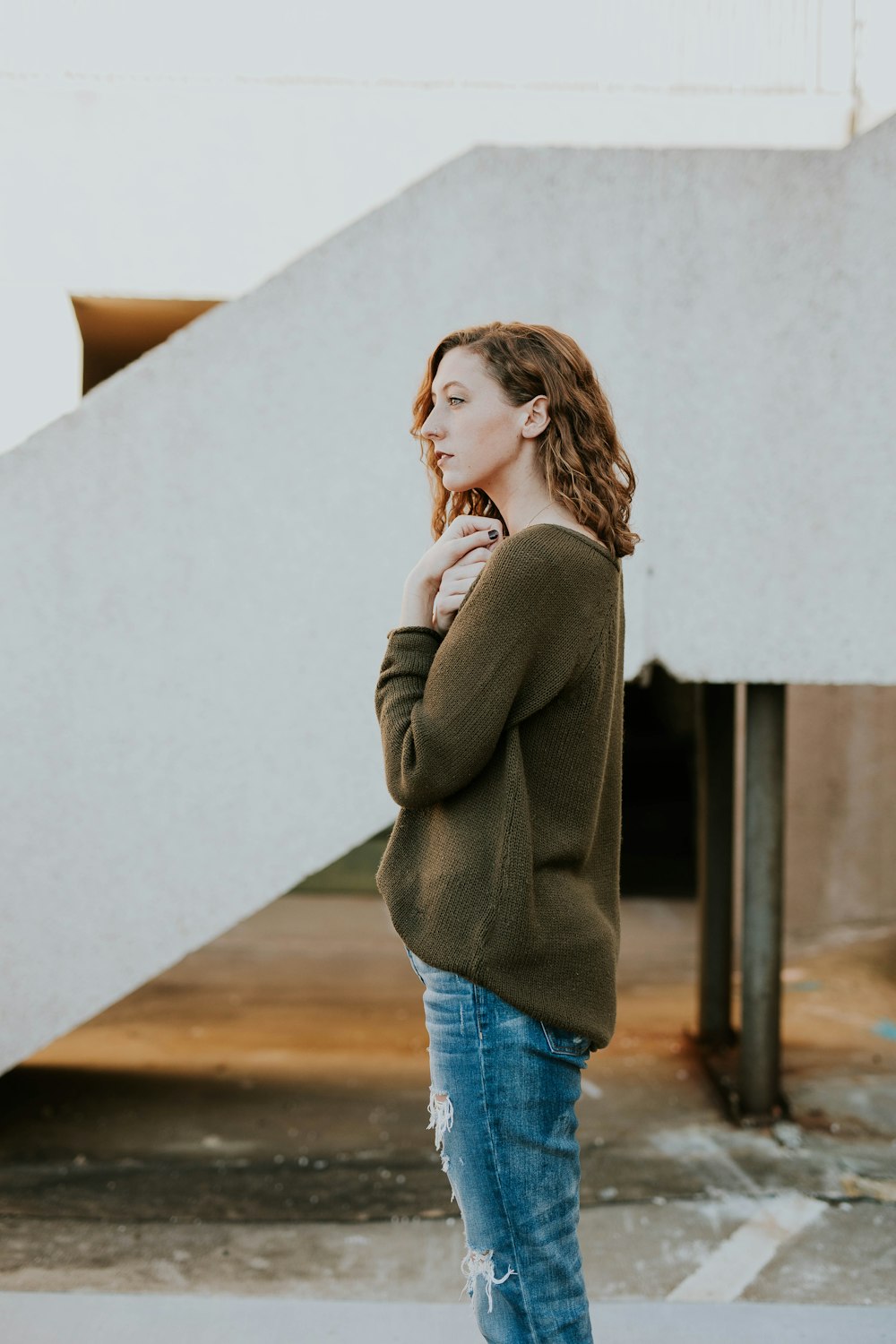 woman wearing brown sweatshirt and whiskered distressed blue jeans