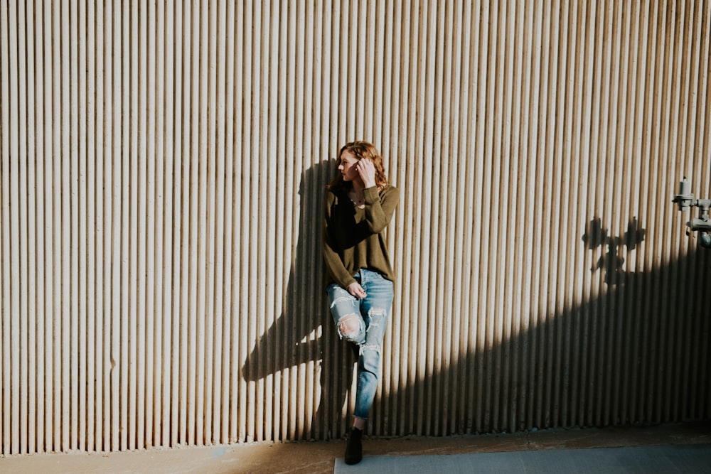 Femme appuyée sur le mur beige avec l’ombre pendant la journée