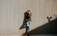 woman leaning on beige wall with shadow at daytime