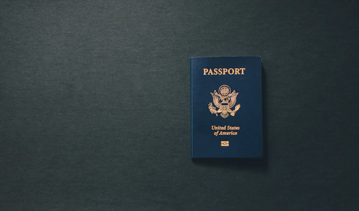 A single passport on a dark desk.