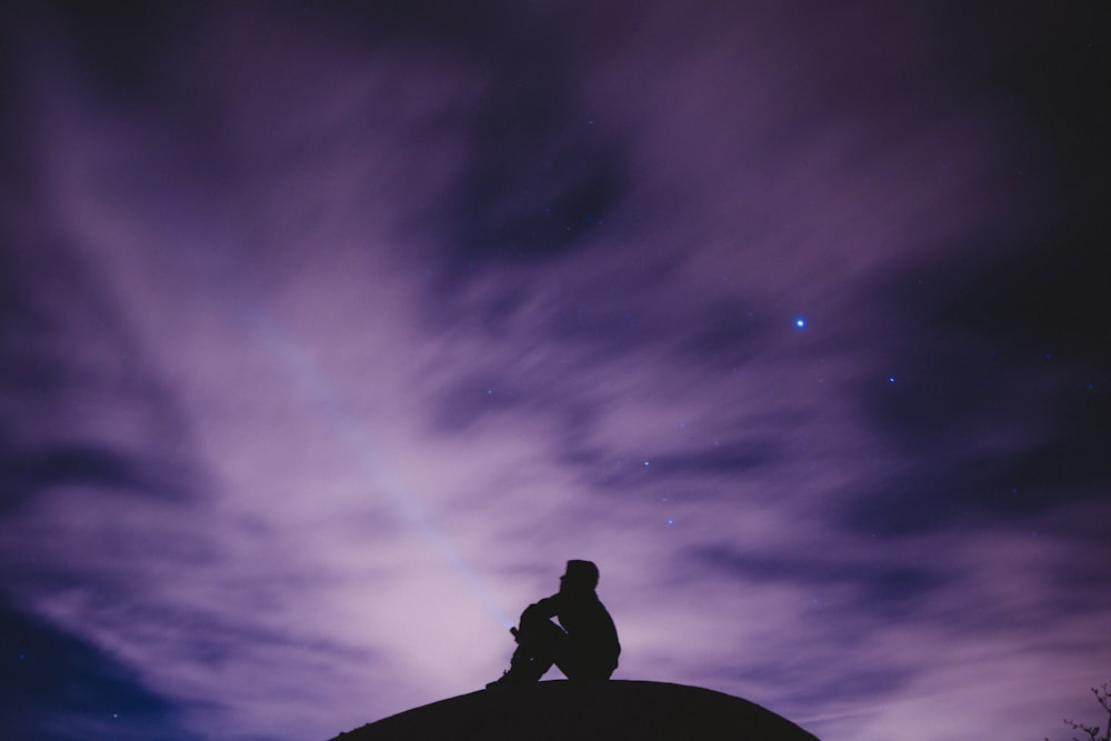 Persona seduta sulla superficie nera che guarda il cielo