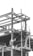 A construction site with a partially built steel framework of a structure. A welder is working on the beams, and a ladder is visible leaning against the structure. The atmosphere appears industrial and busy.