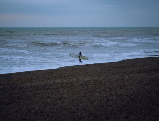 person holding white surfboard in seashore in Brighton United Kingdom
