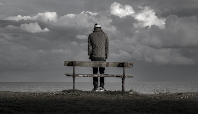 man stood alone by a bench looking out at the horizon, reflecting on managing anxiety.