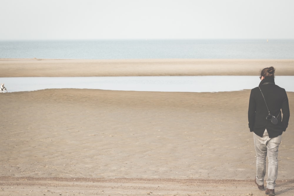 Un hombre parado en una playa junto a un cuerpo de agua