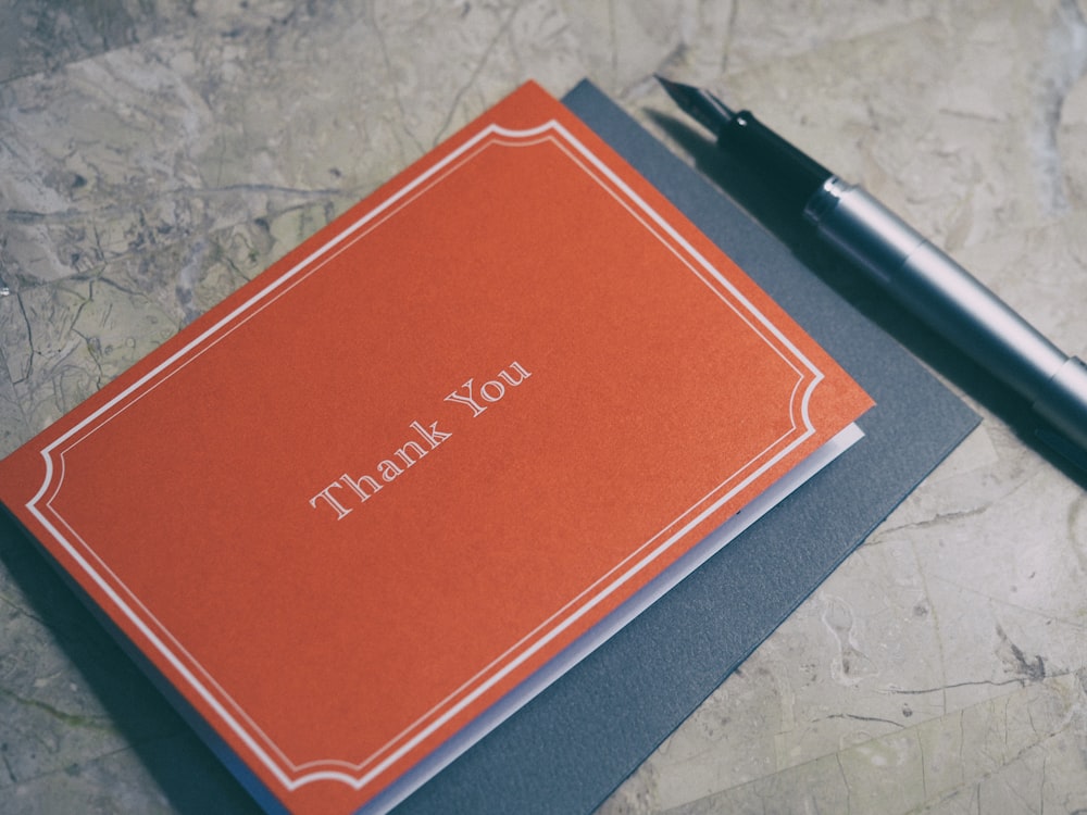 A fountain pen next to a red thank you card