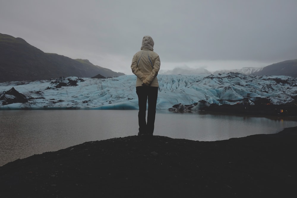 woman standing on cliff fronting body of water