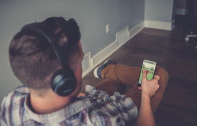 A person relaxing with headphones, watching drone footage on a tablet.