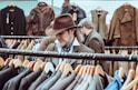 man in brown cowboy hat in front of hanged suit jackets