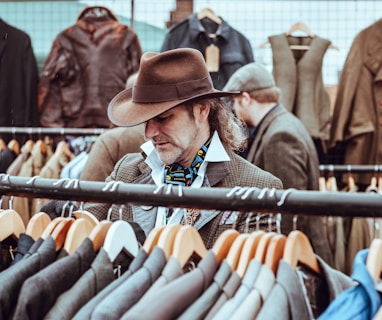 man in brown cowboy hat in front of hanged suit jackets