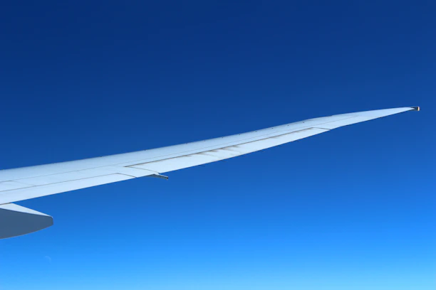 A sleek airplane soaring above clouds with a cyan and black gradient sky background.