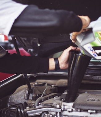 man refilling motor oil on car engine bay