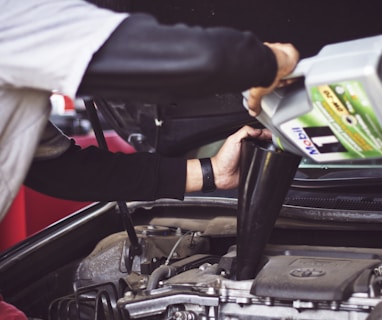 man refilling motor oil on car engine bay