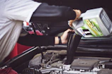 man refilling motor oil on car engine bay
