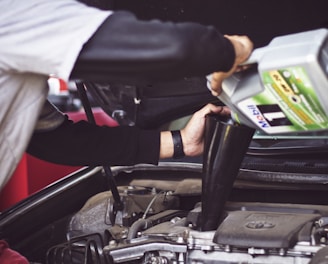 man refilling motor oil on car engine bay