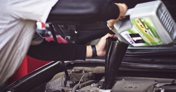 man refilling motor oil on car engine bay