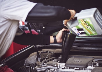 man refilling motor oil on car engine bay