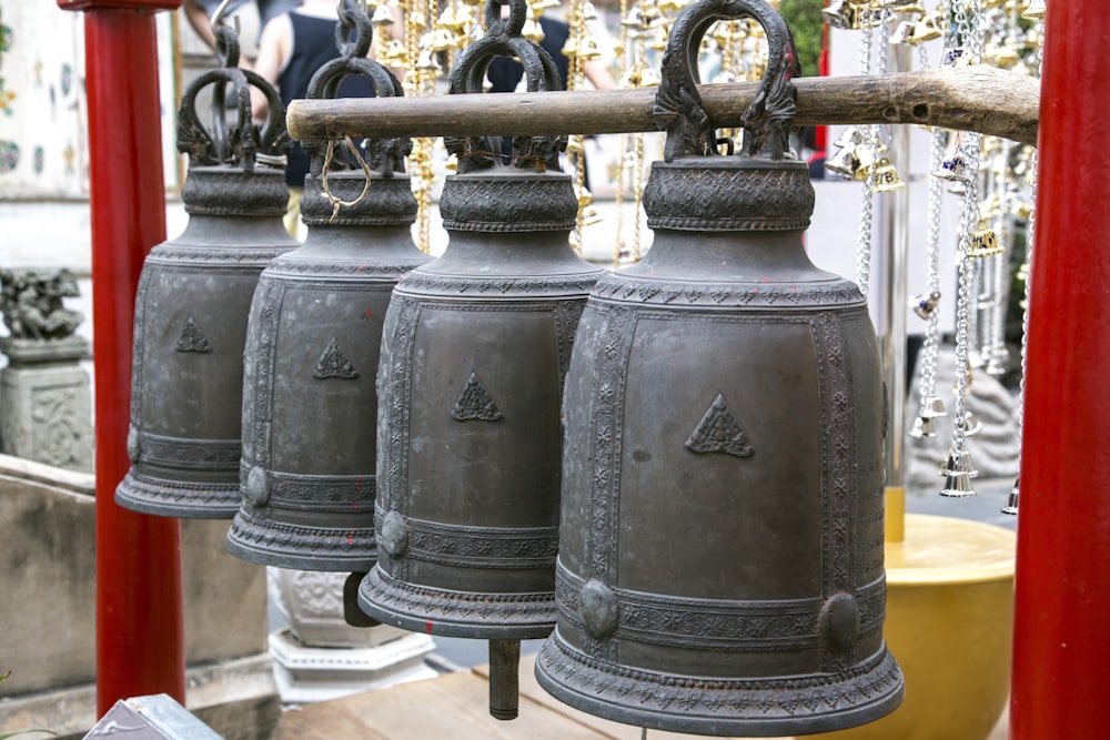 black metal bell on brown wooden fence 
