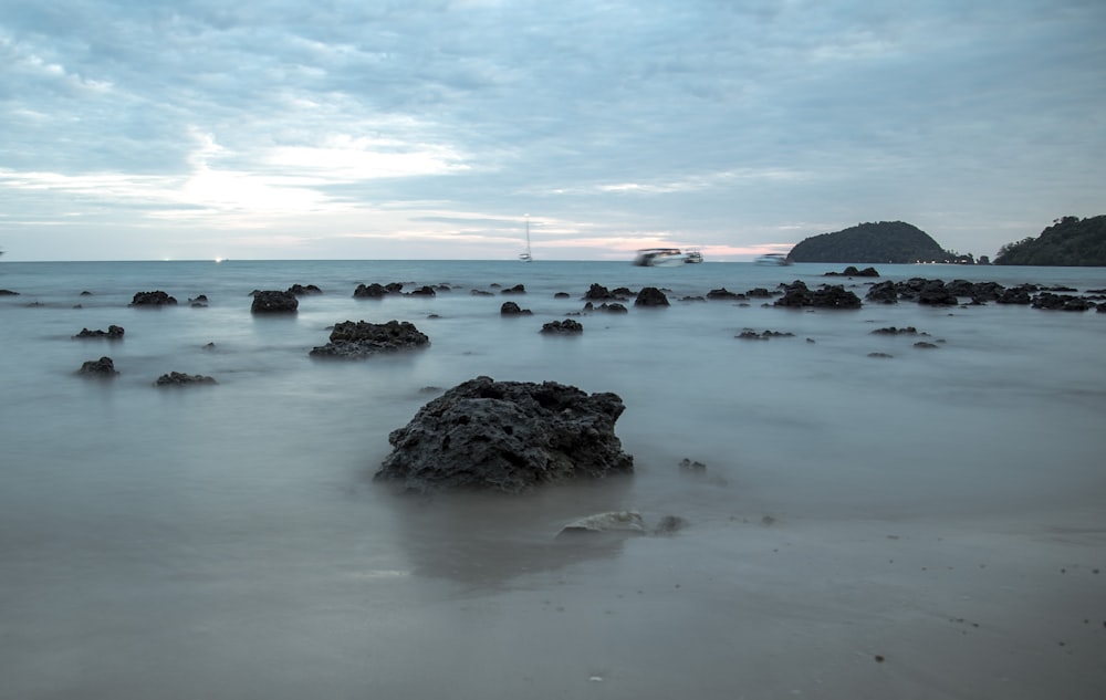 black rock formation on sea shore during daytime