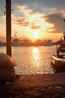 Sunset over a coastal fishing village with boats docked.