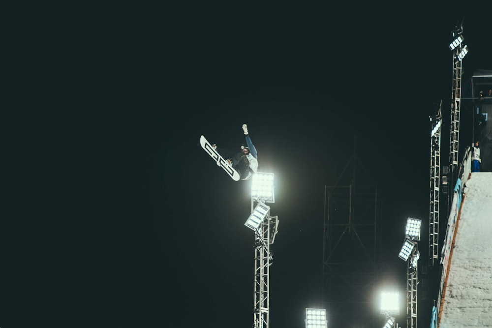 person snowboarding making stunts during nighttime