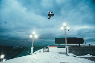 person snowboarding in mid air under cloudy sky