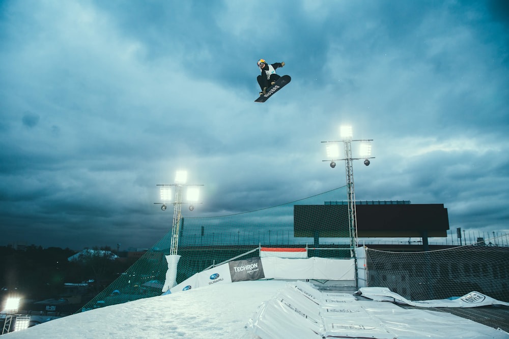 person snowboarding in mid air under cloudy sky
