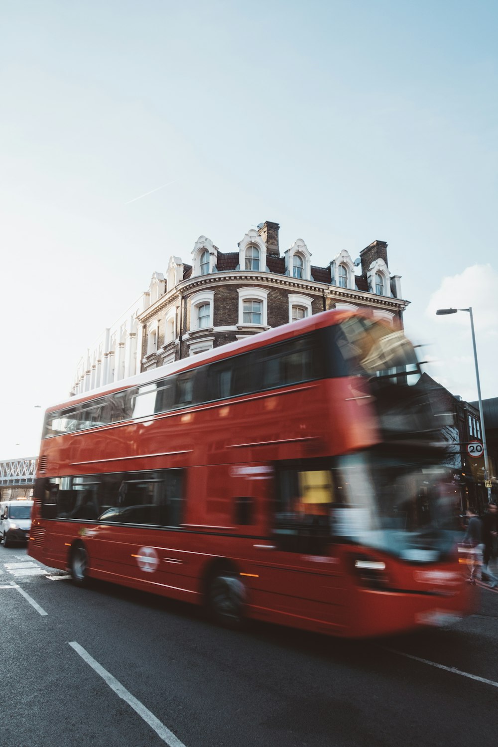 red double-deck bus travelling near near brown and white building during daytime