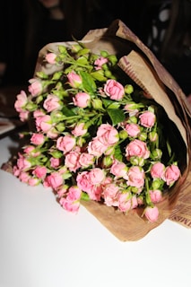 Close-up of delicate pastel roses intertwined with fresh greenery in a rustic wrap.