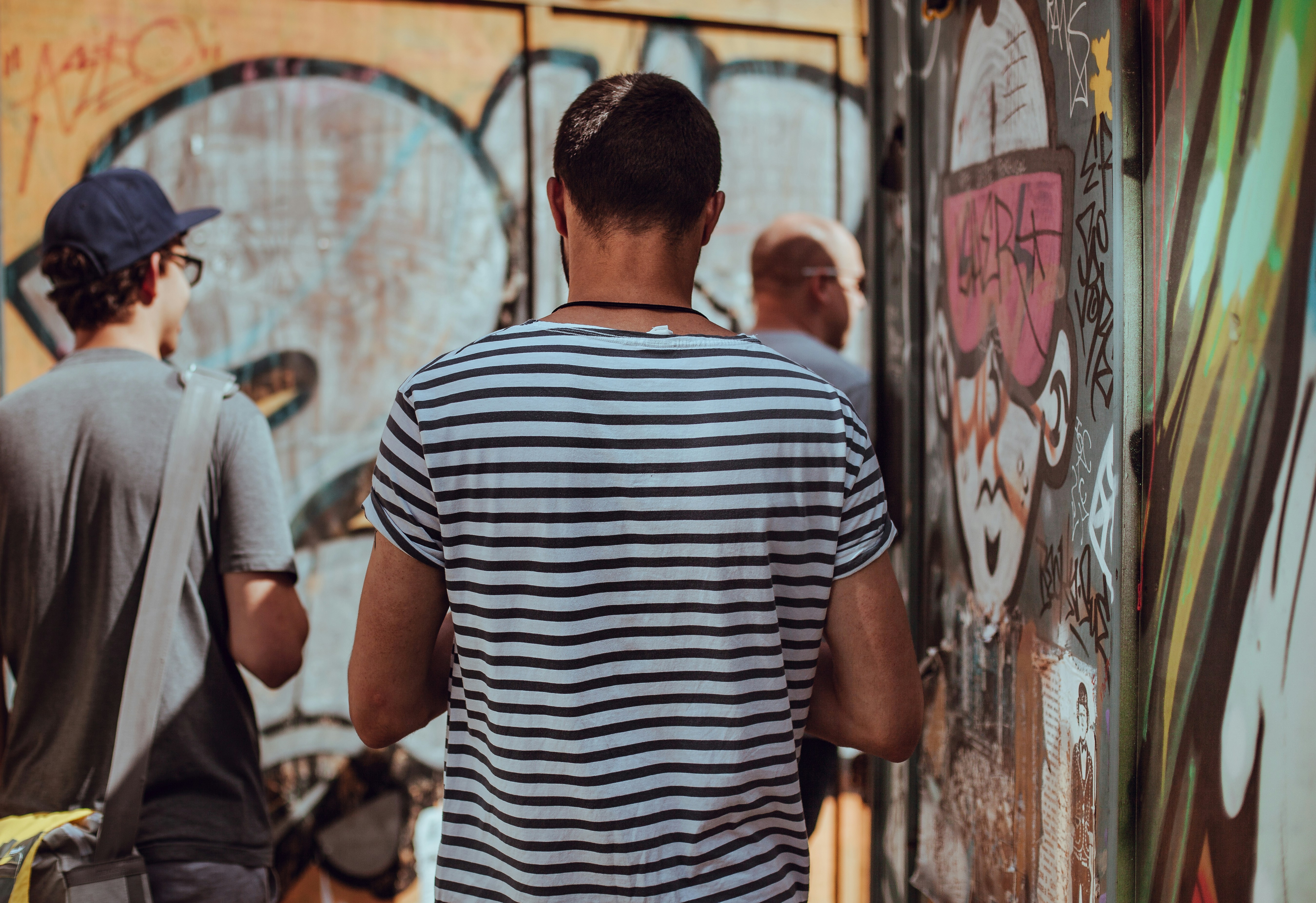 man wearing black and white stripe standing near graffiti