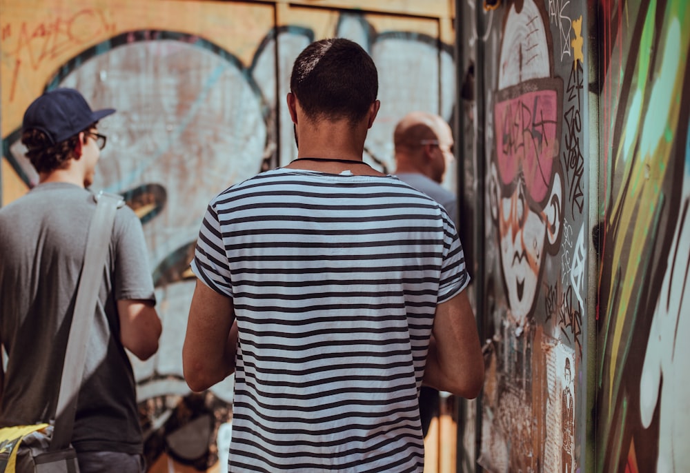 uomo che indossa una striscia bianca e nera in piedi vicino ai graffiti